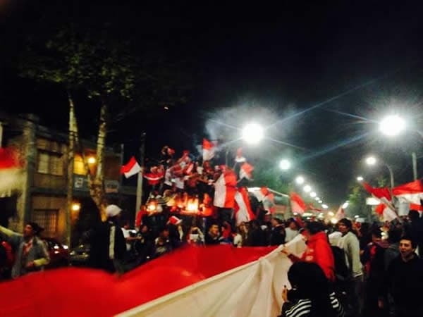 Hinchas de Juventud Unida celebrando en la calle con banderas rojas y blancas