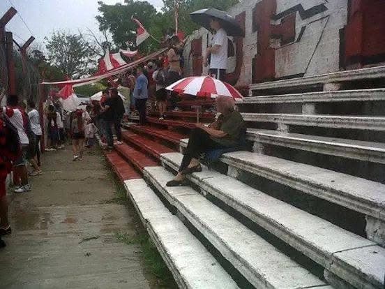 Simpatizante de Juventud Unida en la tribuna durante una jornada de lluvia